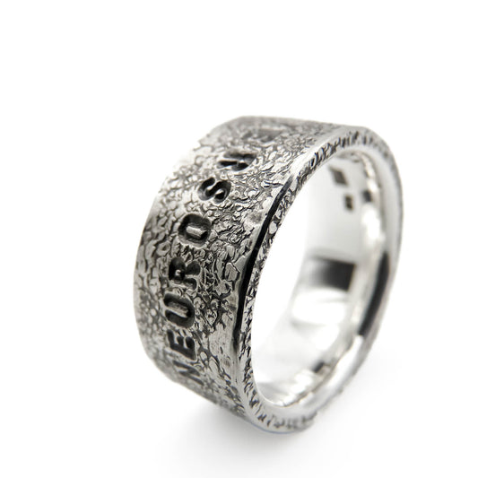 Detailansicht der handgeschmiedeten Oberfläche eines massiven Silberrings aus 925 Silber mit „Neurodivers“-Gravur