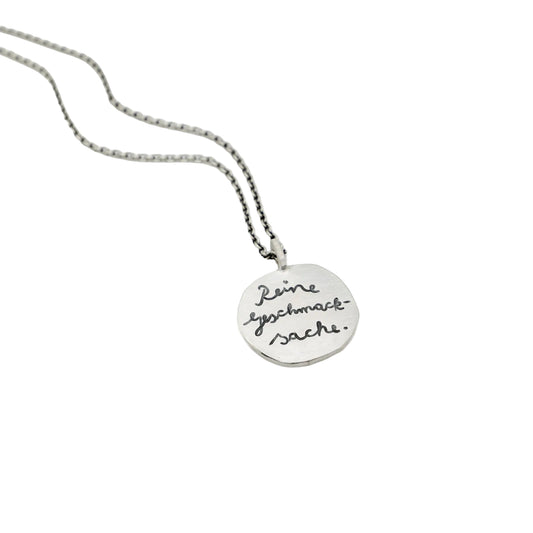 Runder, handgeschmiedeter Kettenanhänger aus Silber mit graviertem Spruch "Reine Geschmackssache".