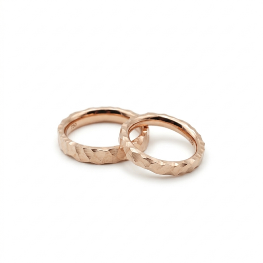 Zwei Eheringe aus recyceltem Roségold im Hammerschlag-Design aus einer Erlanger Goldschmiede.