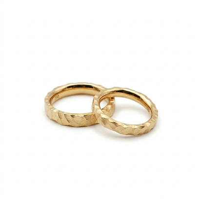Zwei personalisierbare Trauringe aus massivem Gold mit markanter Hammerschlag-Optik, handgefertigt in Nürnberg.